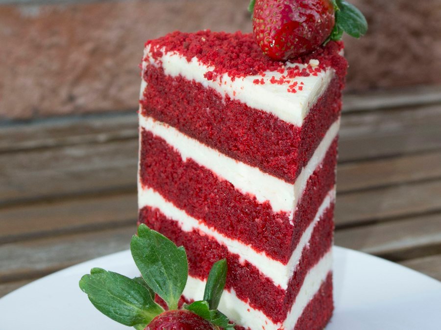 Porción de red velvet con capas de frosting y frutillas
